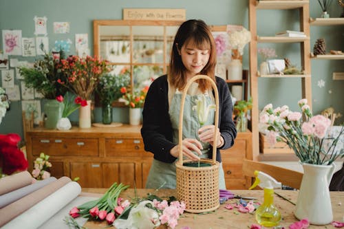 Asian woman arranging flowers in bouquet
