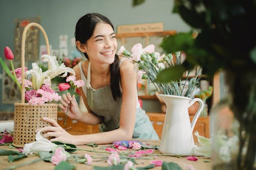 仕事で花の花束を持つ陽気なアジアの花屋