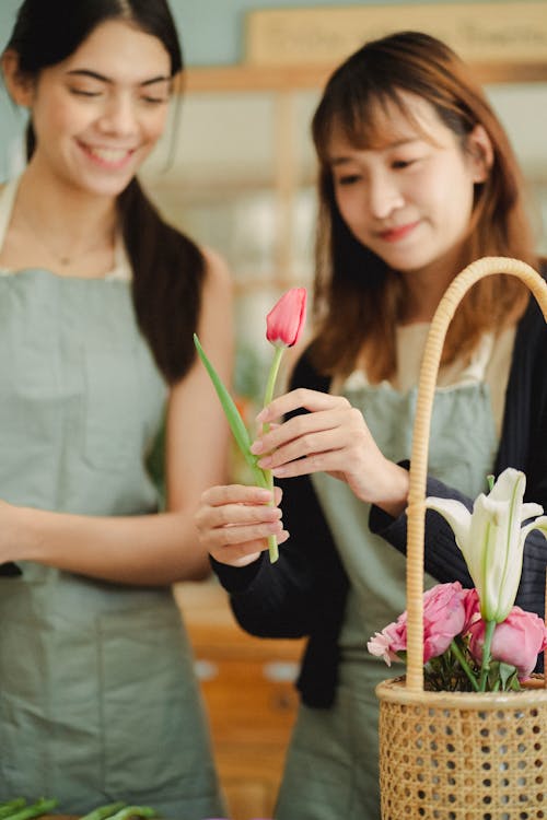 店で花の花束を作成する笑顔のアジアの同僚を作物