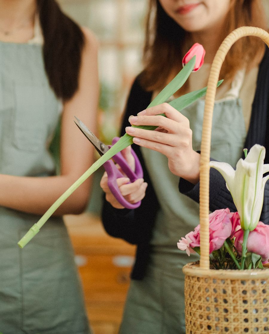 Floristė žirklėmis trumpina gėlės stiebą gėlių studijoje Kaune