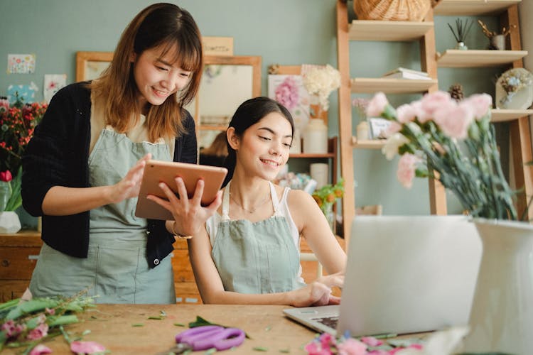 Happy Multiracial Women Working On Gadgets In Floral Store