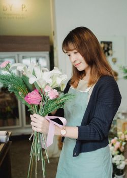 亚洲妇女在她的花店里摆放了充满活力的花束