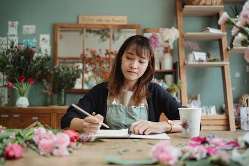 Wanita Asia Yang Terfokus Menggambar Di Buku Catatan
