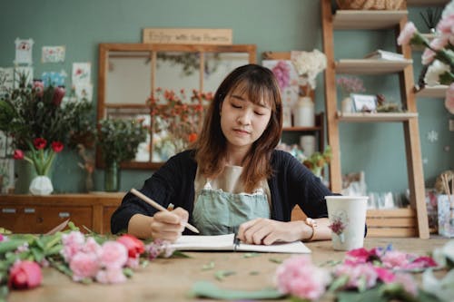 Focused Asian woman drawing in notebook