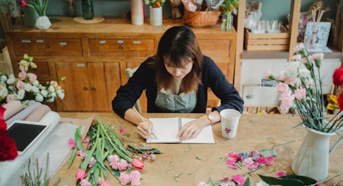 Concentrated Asian woman creating floral design