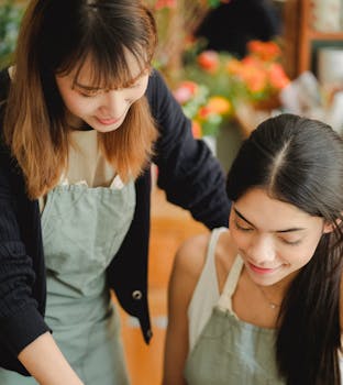 Two female florists working together in a vibrant floral shop, fostering teamwork and creativity.