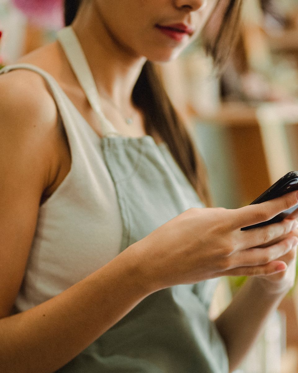 Seller checking orders on her phone at her shop