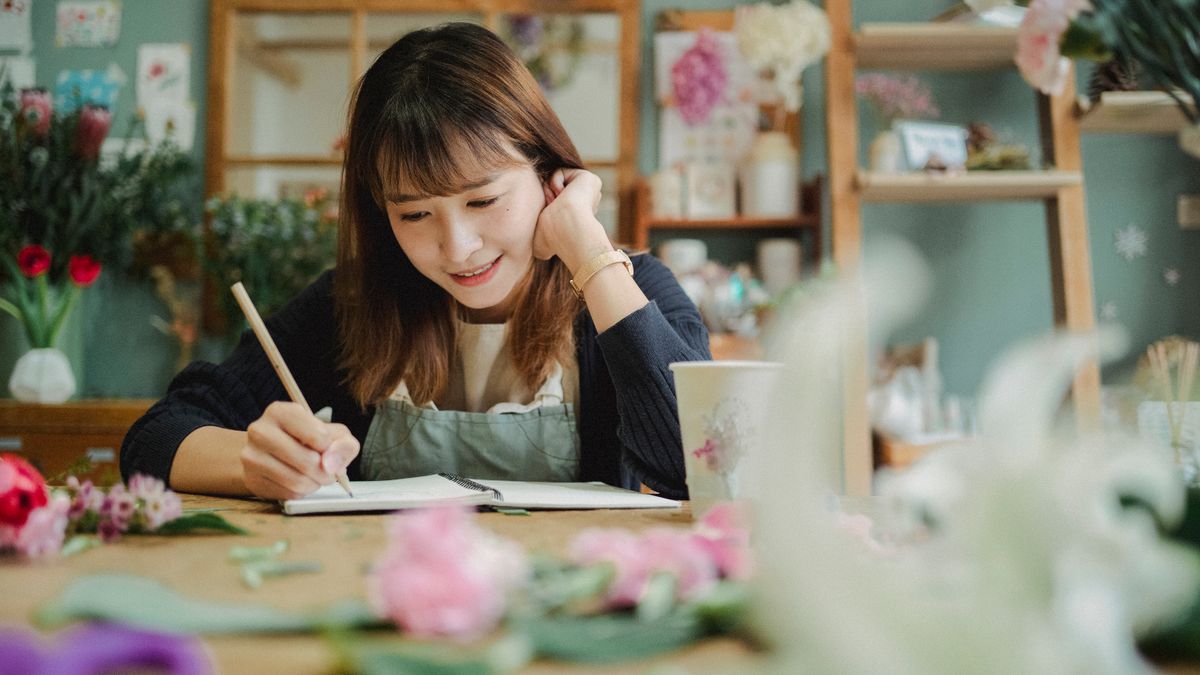 花屋の店内でエプロンを着けた人がノートに書いているところ