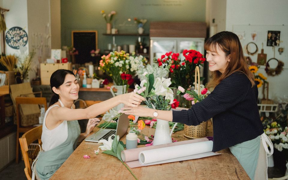 Two florists running their shop with a laptop on the counter