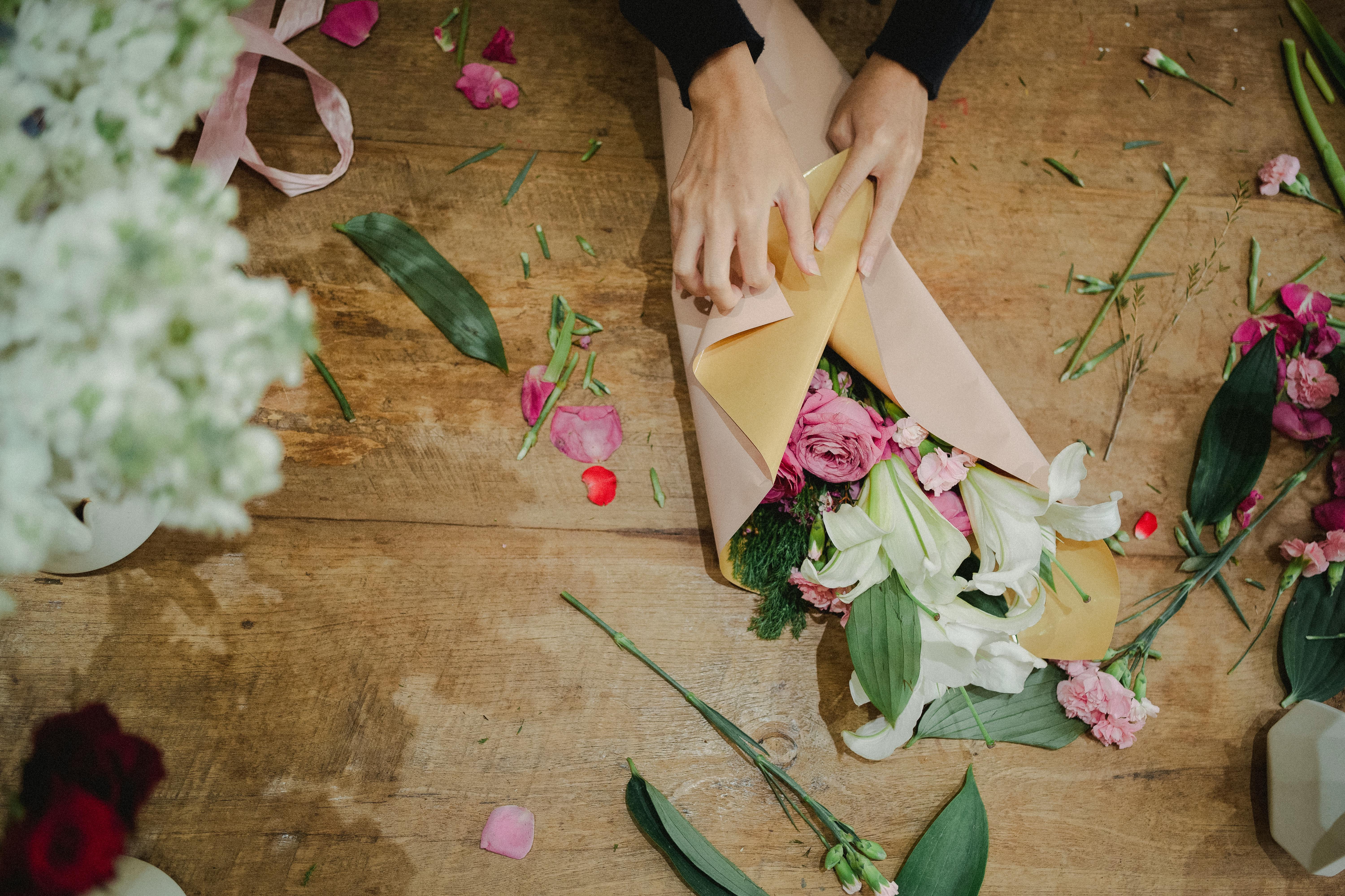 crop woman arranging flowers in paper