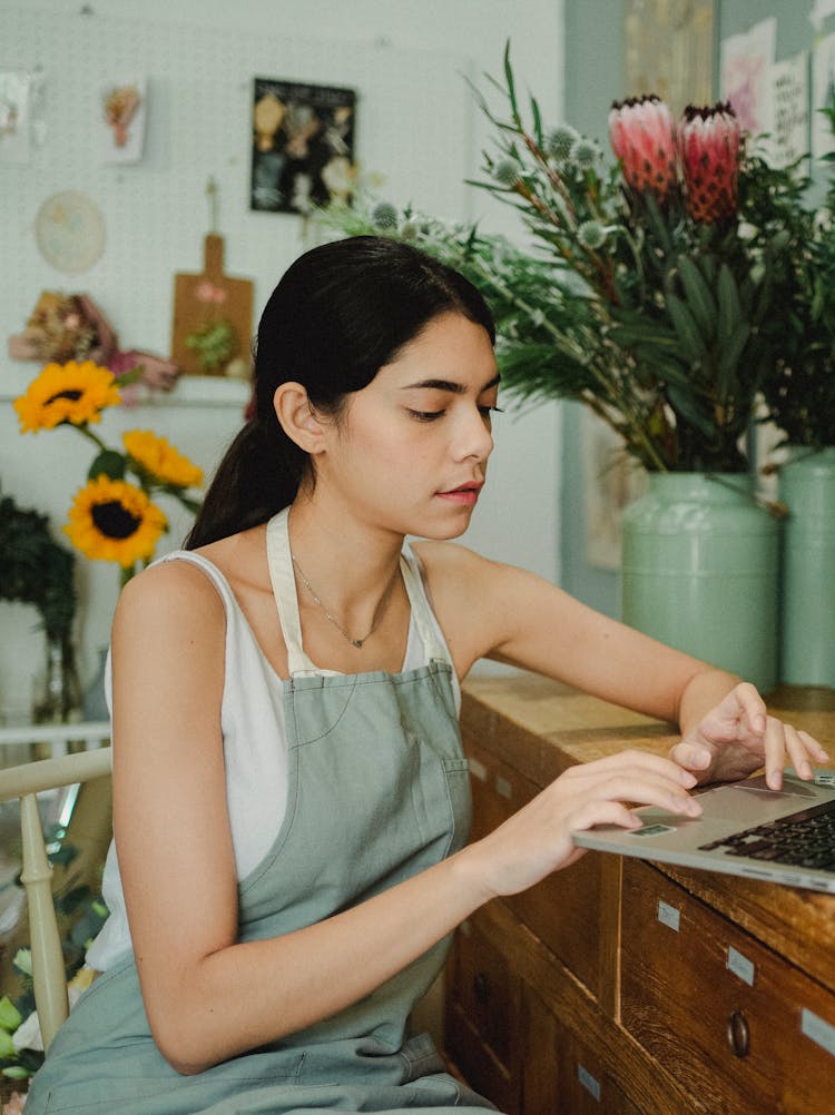 Focused Woman With Laptop In Flower Shop