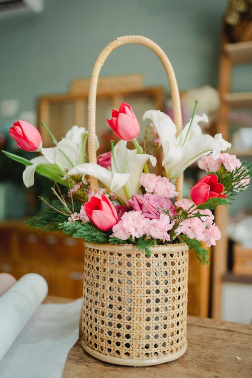 Wicker basket with fresh various flowers on wooden table in modern floral shop