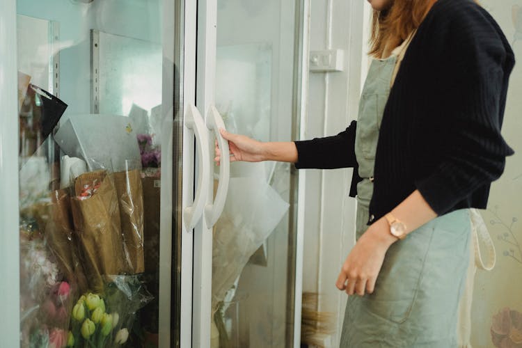 Crop Woman Near Fridge With Flowers