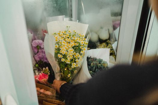 女花店店员在花店工作时，将不露面的作物花束放入冰箱