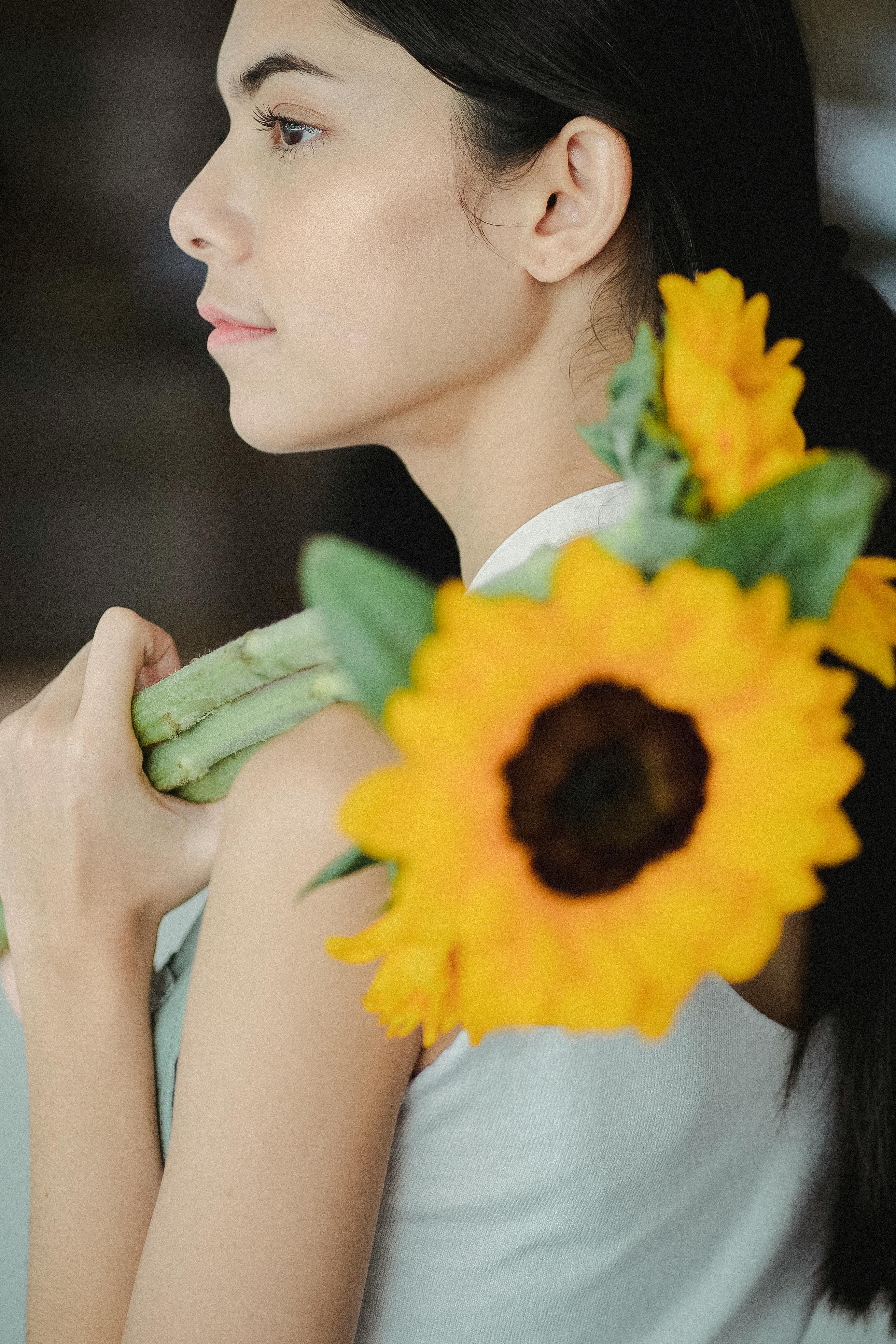 A serene woman holds a vibrant sunflower bouquet, exuding calm and elegance.