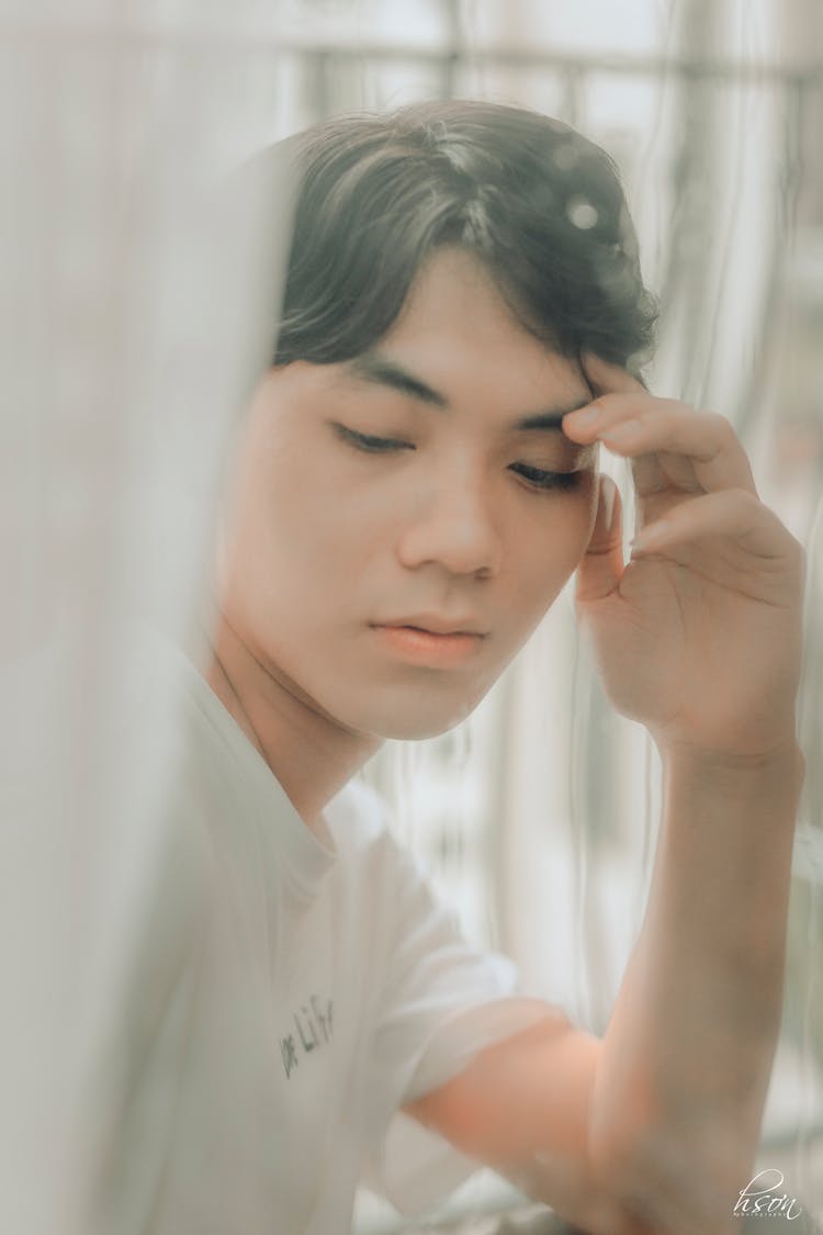 Wistful Asian Man Touching Face On Balcony