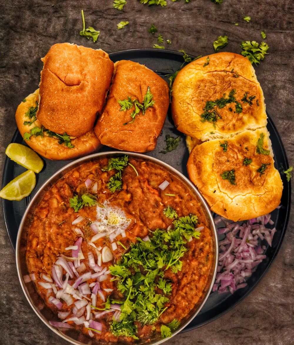 Spicy pav bhaji garnished with onions, coriander and lime
