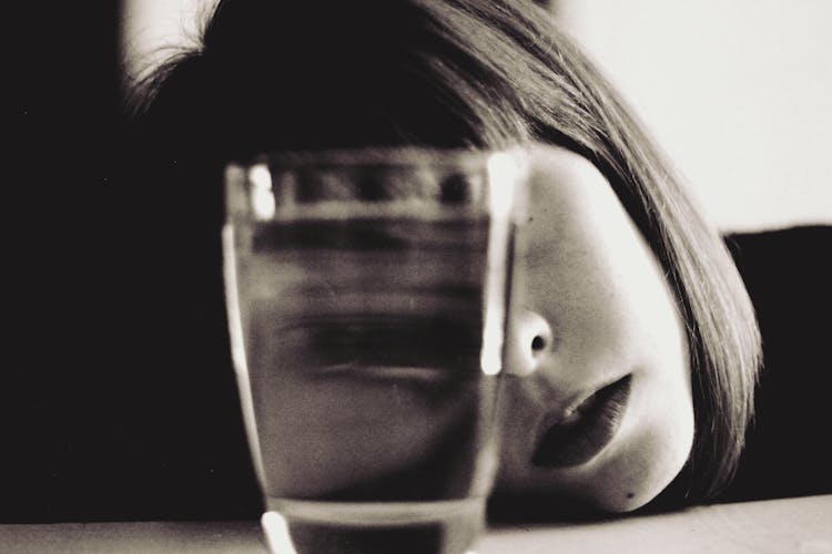 Woman Looking Through A Full Glass Of Water 