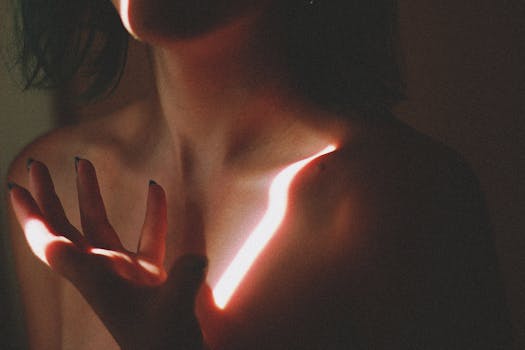 A captivating artistic portrait of a woman with dramatic lighting effects, highlighting her bare shoulder and hand.