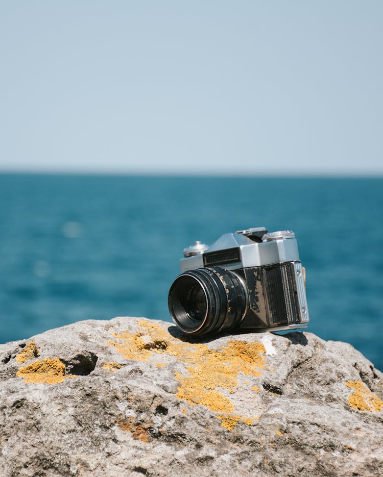 Black And Silver Camera On Gray Rock With Brown Sand