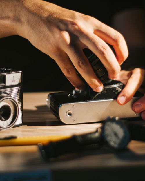 Free Close-up of a person adjusting a lens on a vintage camera indoors. Stock Photo