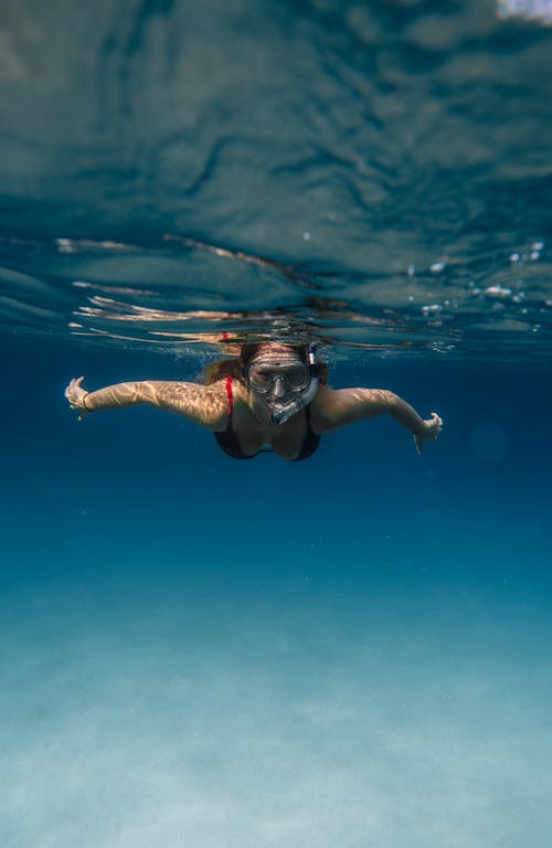匿名的女人在陽光下潛水水下的海洋