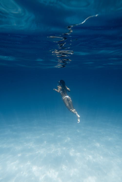 Анонимная женщина, ныряющая в синее море летом