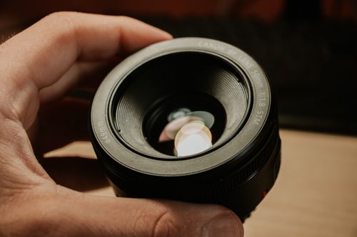 Free Close-up of a hand holding a camera lens with reflections inside, focusing on photography equipment. Stock Photo