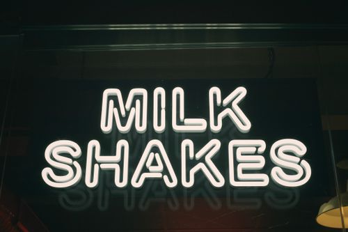 Free Close-up of an illuminated neon milk shakes sign in a dark setting. Stock Photo