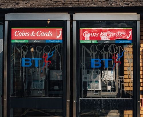 Free British phone booths with BT logos, showing signs of urban wear in an outdoor setting. Stock Photo