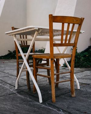 Wooden chairs and a folding table on a stone patio, photo by Ellie Burgin on Pexels