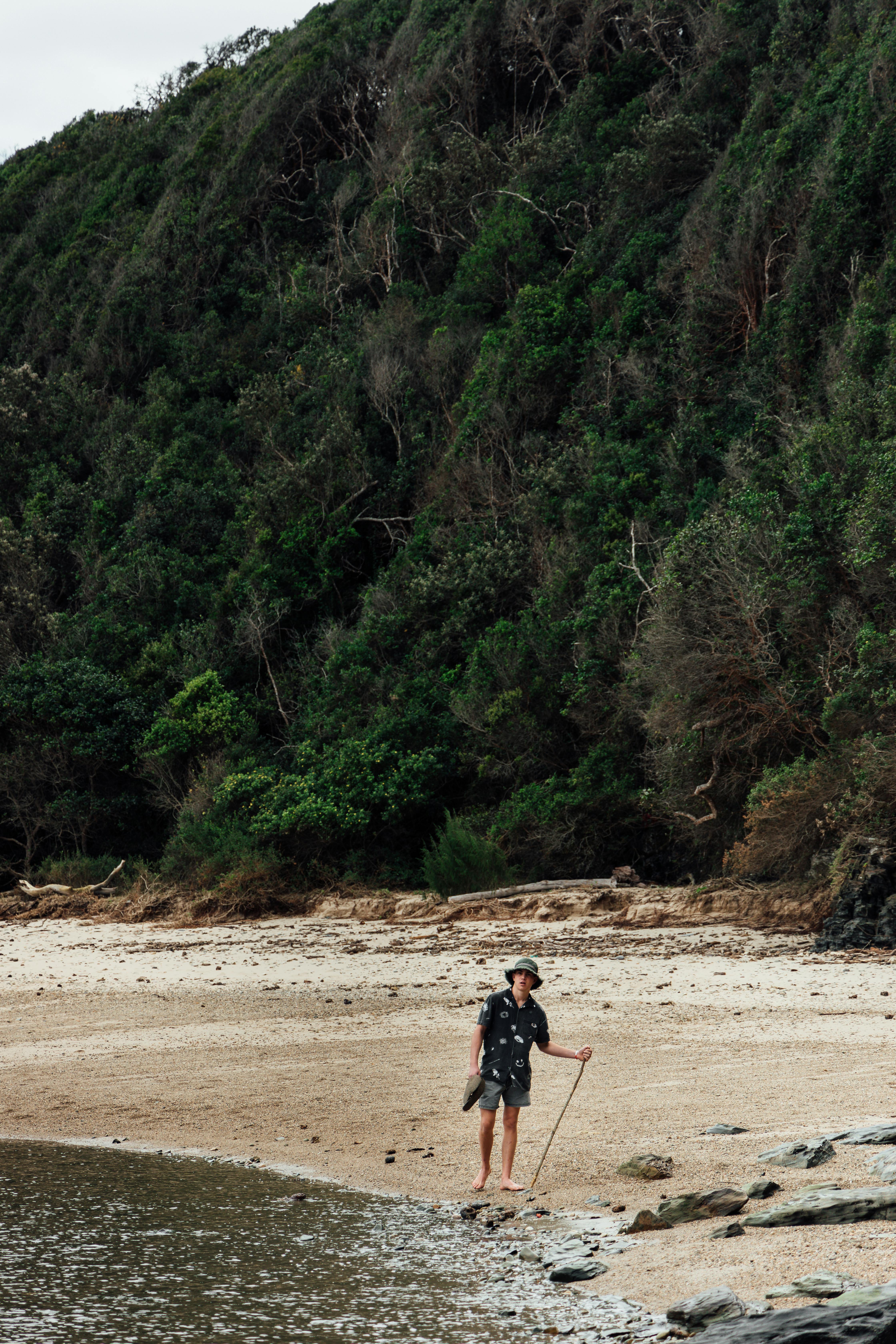 Explore tranquility with a man walking on the serene beach at Nature's Valley, South Africa.