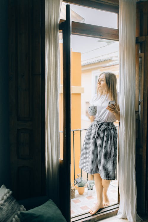 Free Woman Standing in the Balcony While Holding a Mug Stock Photo