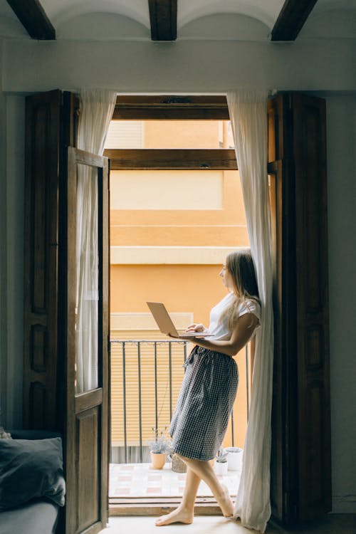 Woman leaning on the Wall Holding Laptop