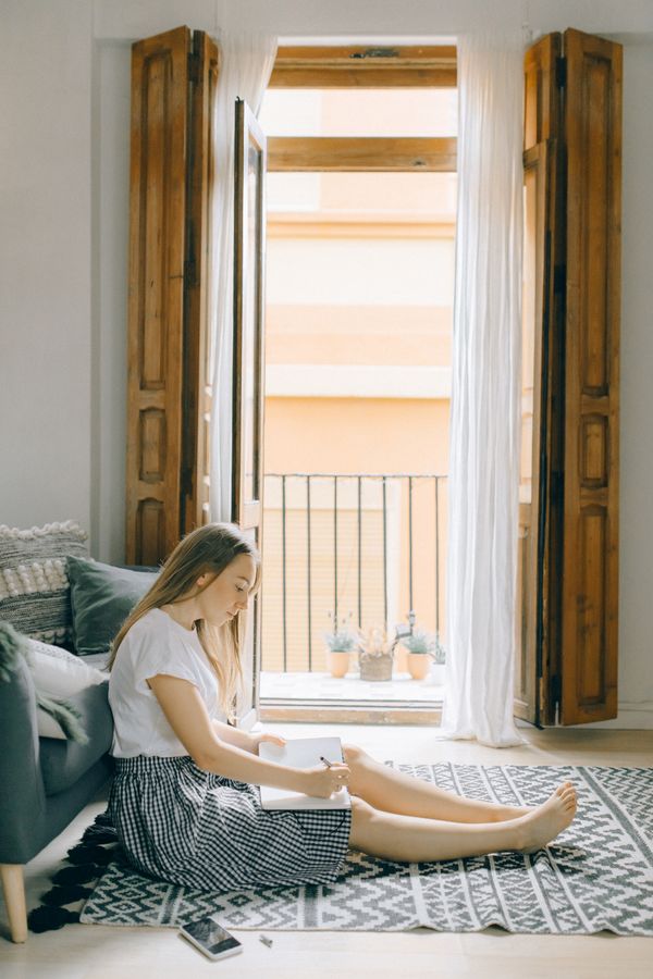 Woman journaling in cozy home window sunlight