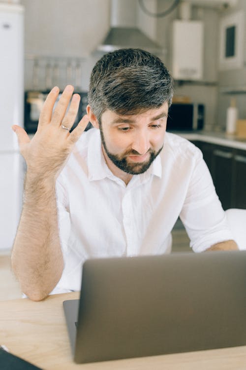 Free A Man using a Laptop while Taking on a Video Call Stock Photo