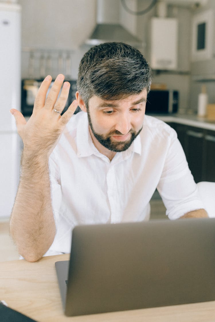 A Man Using A Laptop While Taking On A Video Call