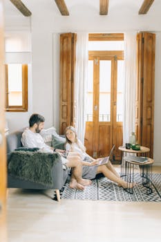A couple working on laptops in a bright living room, embracing a remote work lifestyle.
