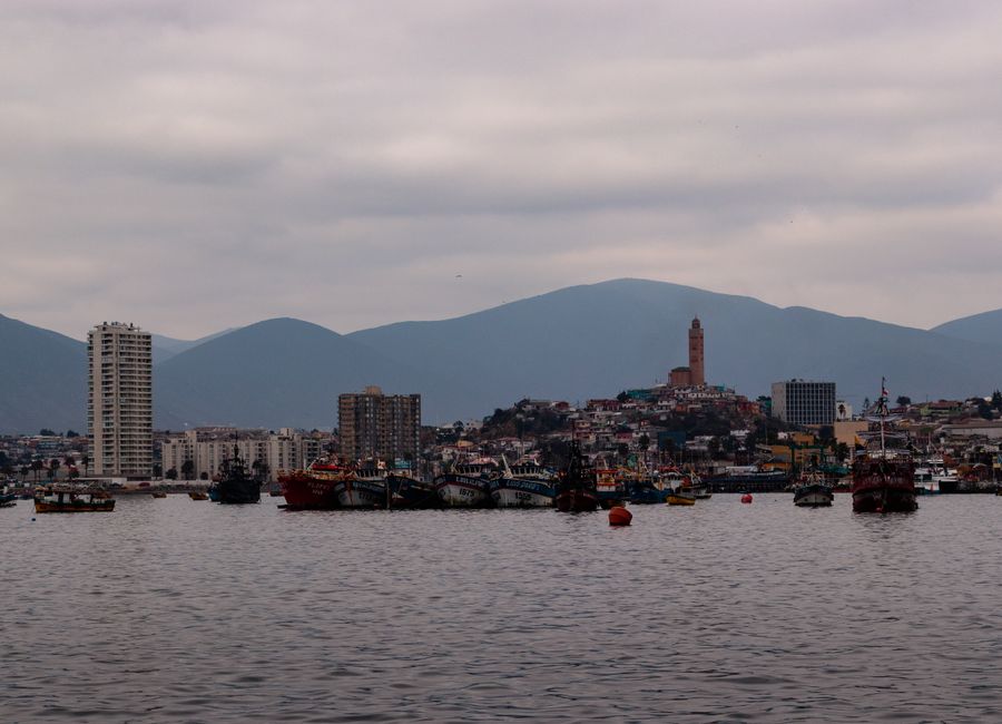 Scenic view of boats against Coquimbo cityscape with mountains in the background.