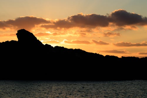 Silhouette of Mountain Near the Sea during Sunset