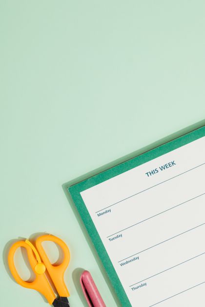 Weekly planner pad with scissors on a mint background — photo by kaboompics.com on Pexels