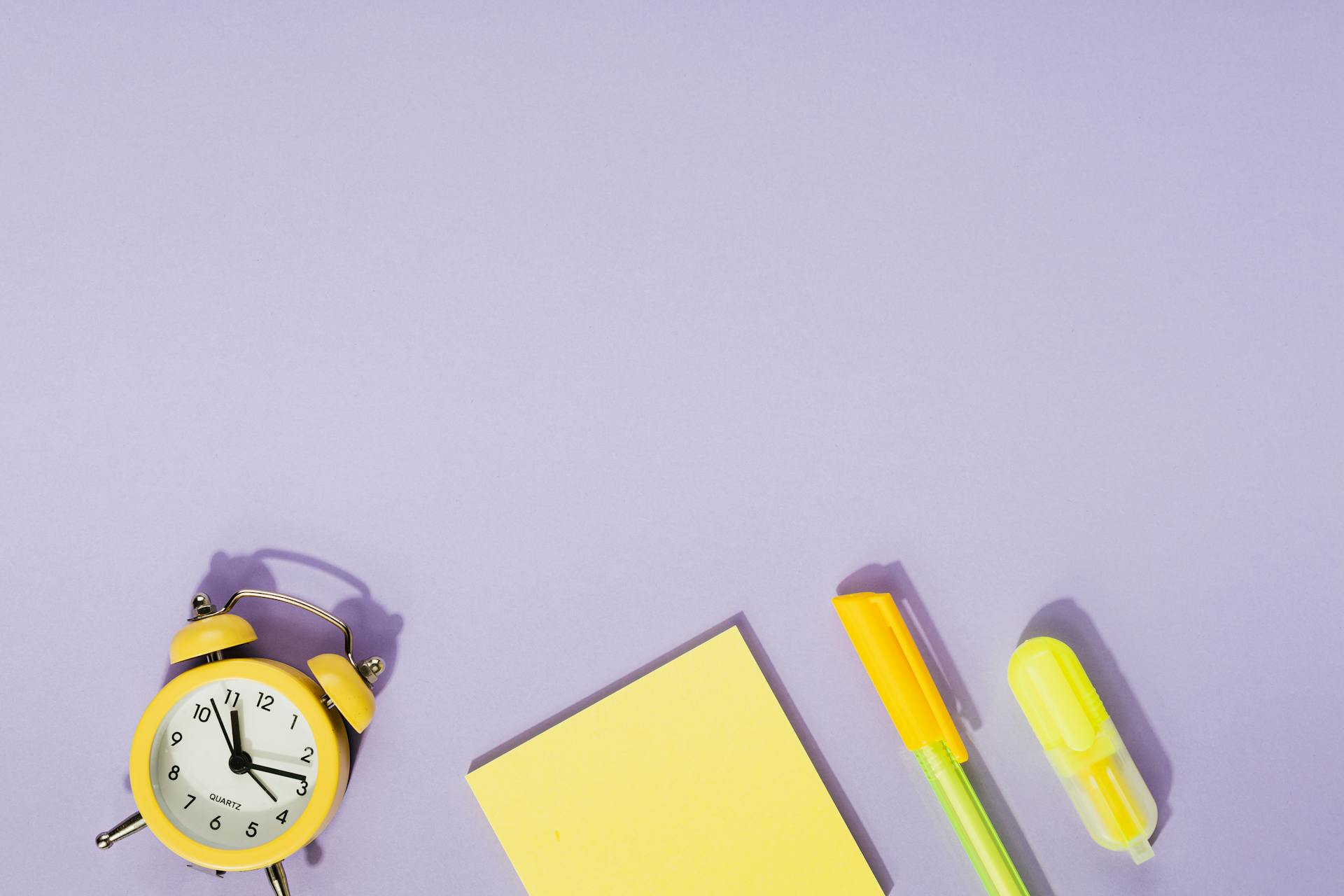 Yellow Sticky Note Pad Beside an Alarm Clock and a Ball Pen