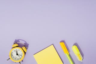 Yellow Sticky Note Pad Beside an Alarm Clock and a Ball Pen