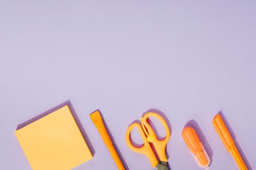 Free Bright orange office supplies neatly arranged on a pastel purple background, ideal for creative design projects. Stock Photo