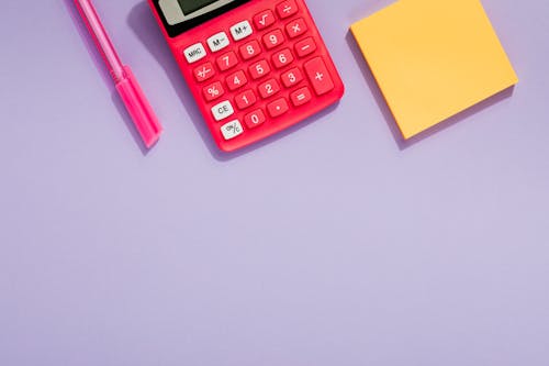 Red Calculator Beside a Yellow Sticky Note