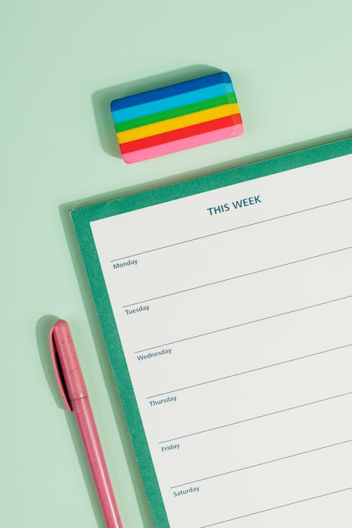 Free A Weekly Planner Beside a Colorful Eraser and a Yellow Pair of Scissors
 Stock Photo