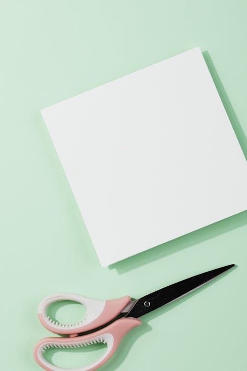 A White Notepad Beside a Pair Scissors