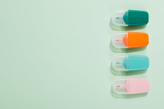 Four colorful erasers aligned on a pastel green background with copy space.