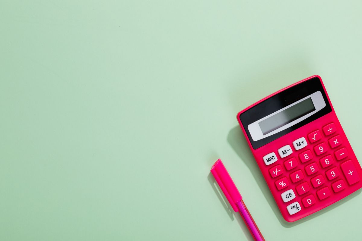 Calculatrice rose et stylo sur un fond pastel