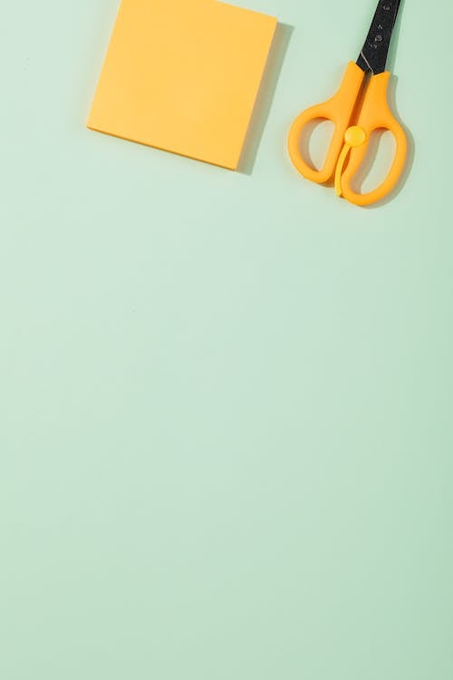 Free Yellow Sticky Note and Scissors on Pastel Green Surface Stock Photo